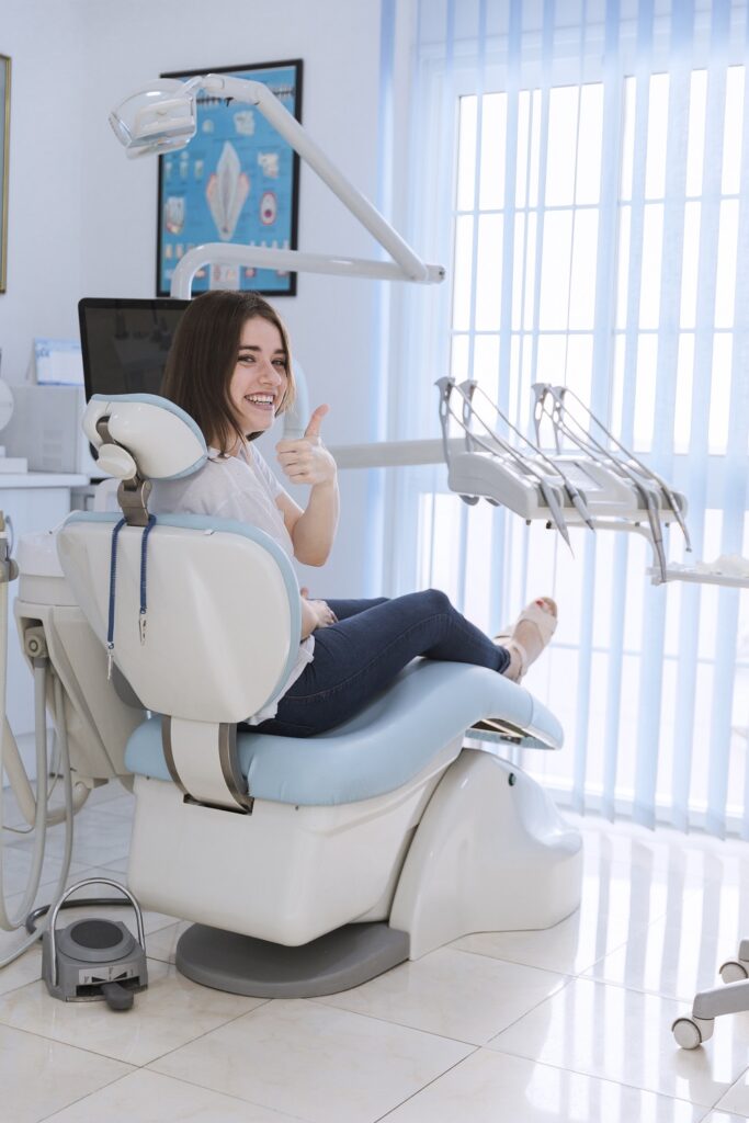 smiling-female-patient-sitting-chair-showing-thumb-up-dental-clinic